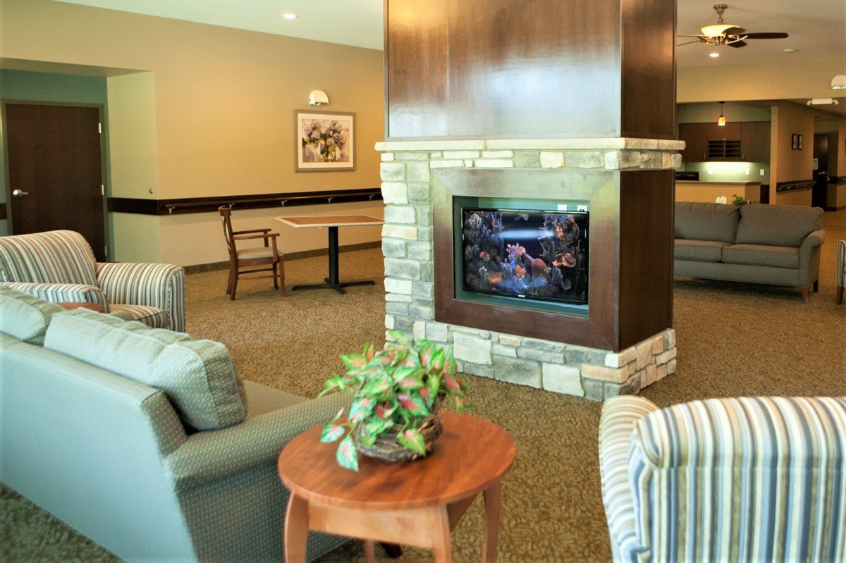A cozy living room interior featuring a stone fireplace, comfortable seating, and a wooden table with a plant.