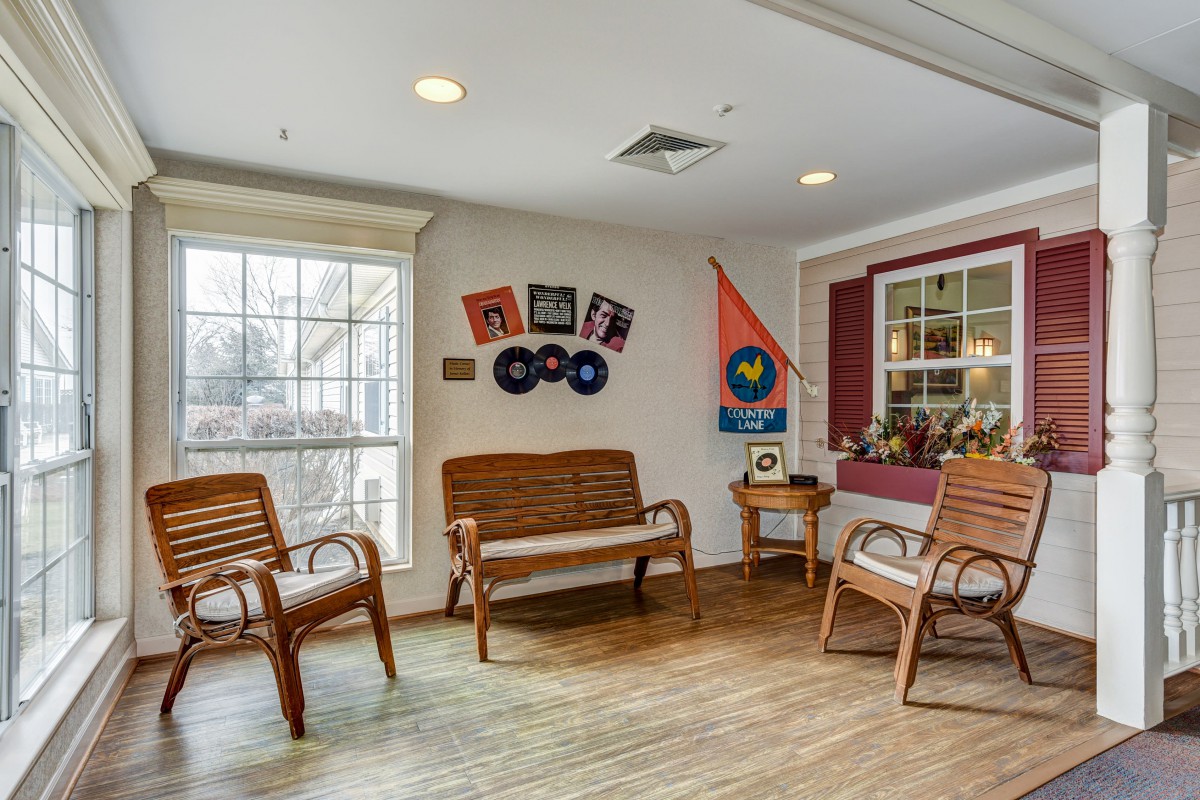 A cozy interior space with wooden chairs, wall decorations, and a large window.