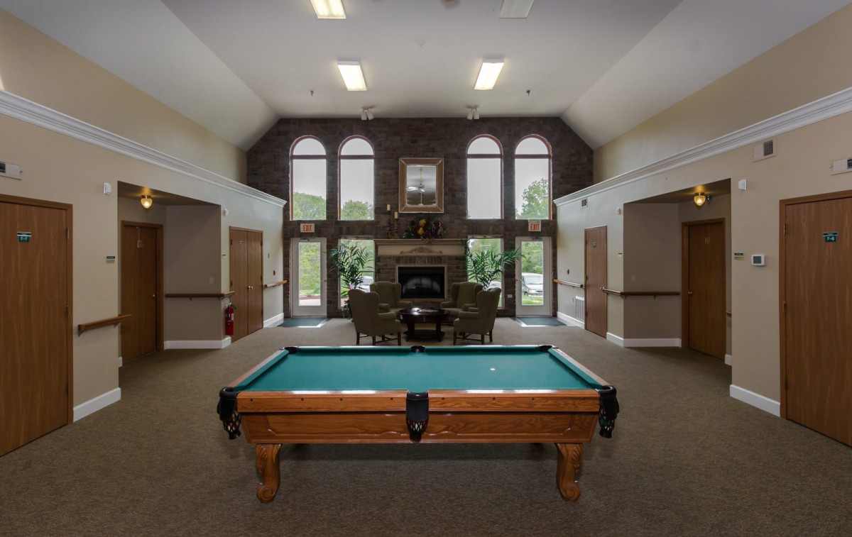 A recreation room featuring a billiard table, a fireplace, and large windows.