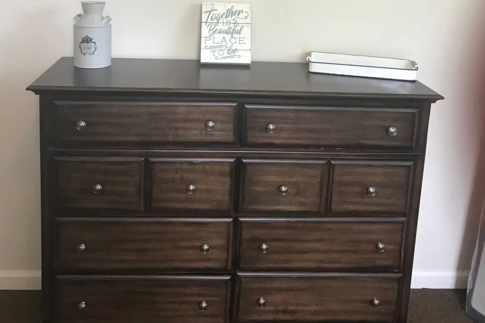 A dark wooden dresser with multiple drawers and decorative items on top.