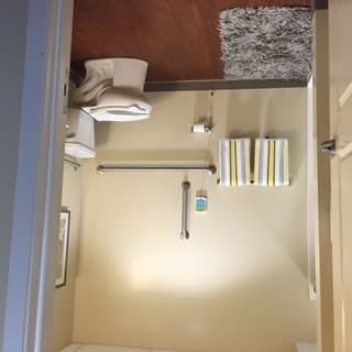 A well-organized bathroom with a toilet, towels, and a rug.