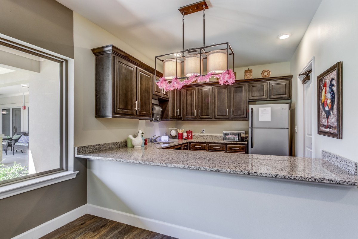 A modern kitchen with granite countertops, wood cabinets, and stainless steel appliances.