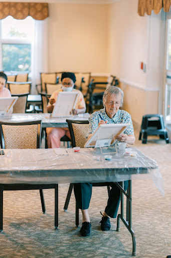 Elderly individuals engaged in a painting class, enjoying a creative and social activity.