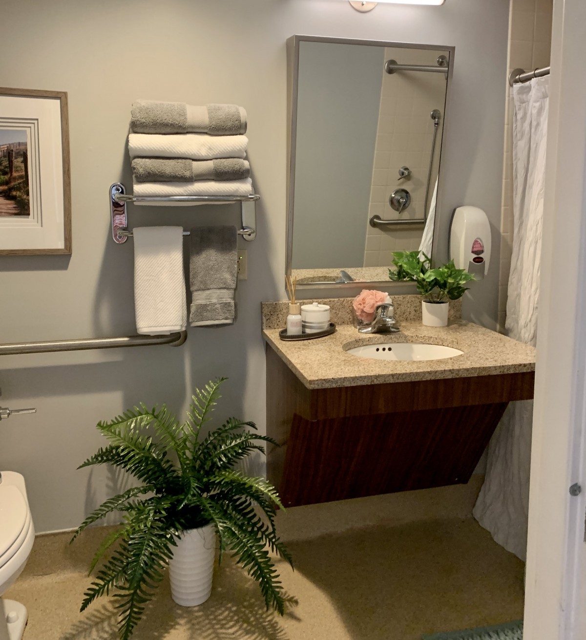 A neatly organized bathroom with a sink, mirror, and decorative elements like plants and towels.