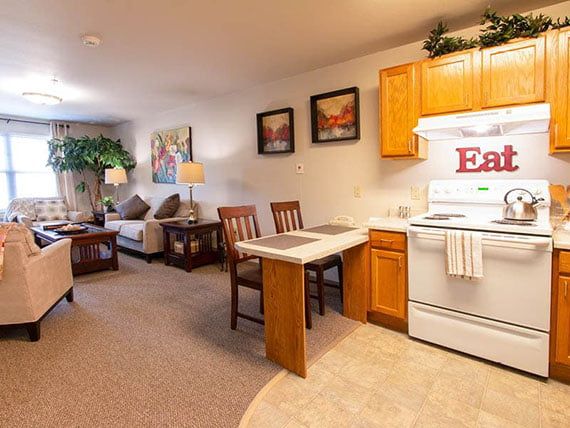 A cozy open-concept living room and kitchen area with wooden furniture and warm decor.