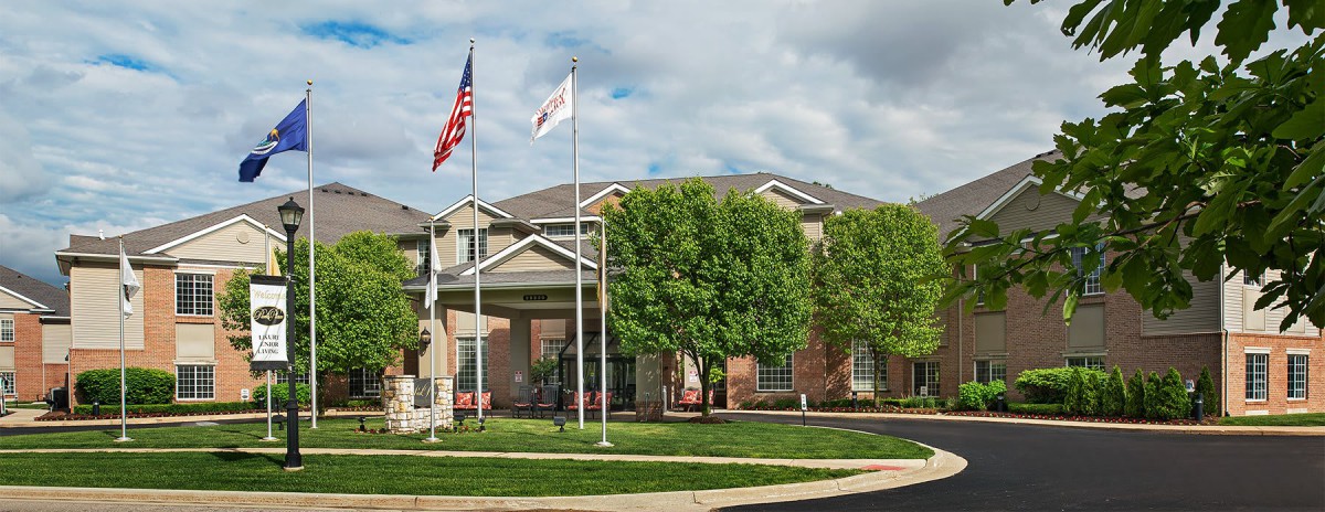 A residential building with flags and trees under a cloudy sky.