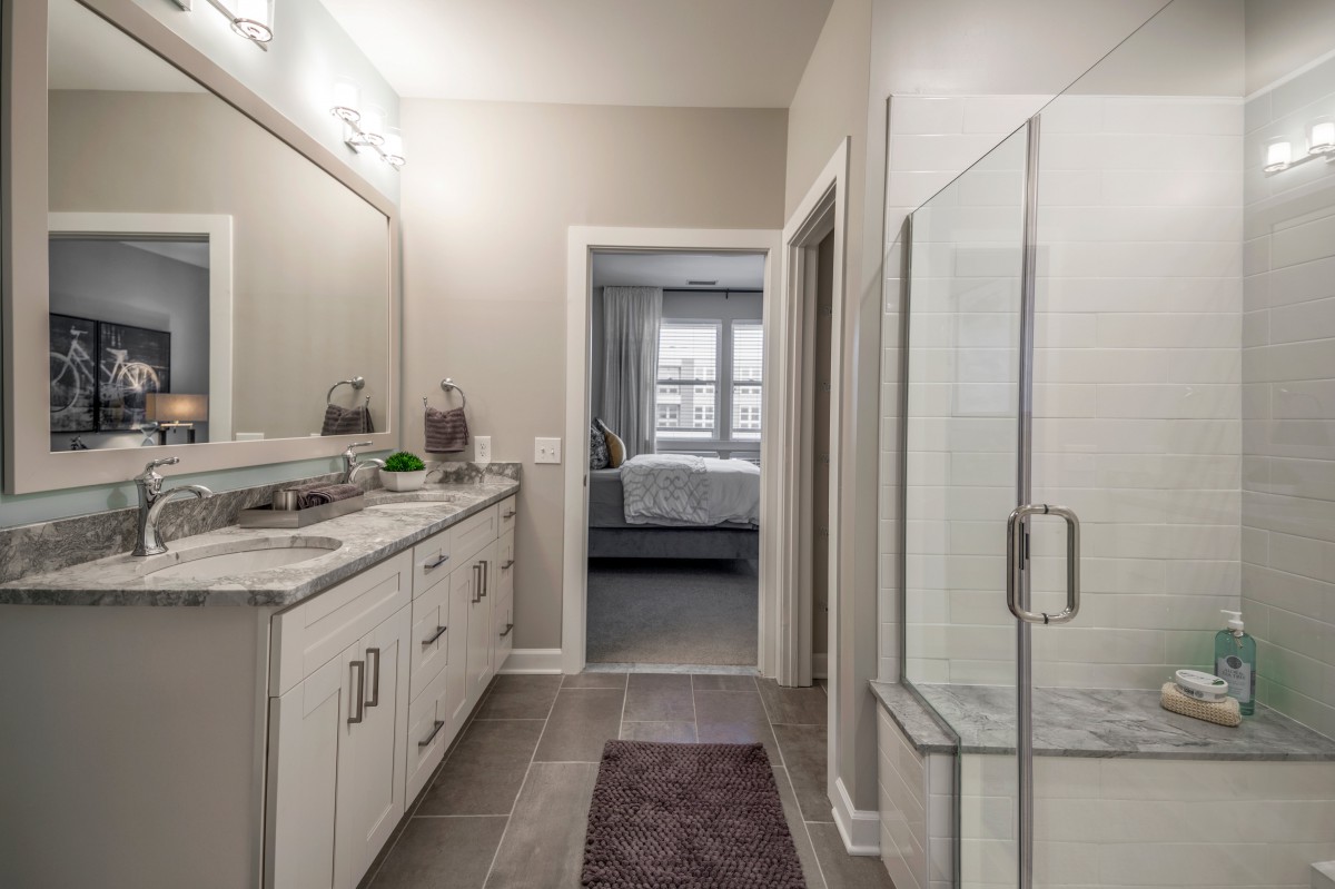 A modern bathroom featuring a sleek vanity, large mirror, and glass-enclosed shower.