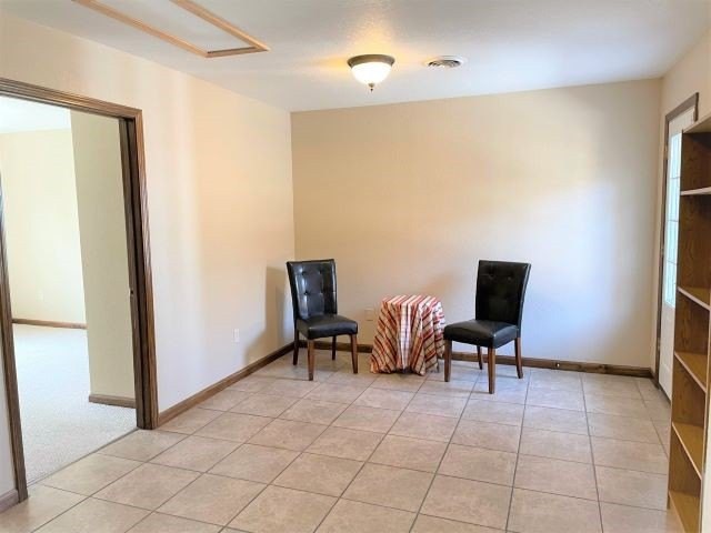 A minimalist room with two chairs and a small round table on a tiled floor.