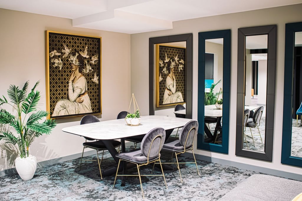 A modern dining room with contemporary artwork, large mirrors, and elegant decor.