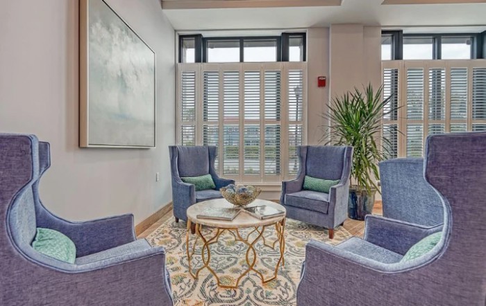 A cozy living room with four armchairs, a stylish table, and a large plant by the window.