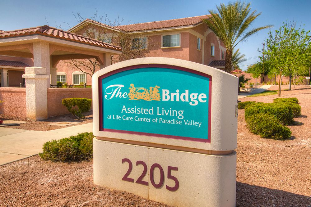 The exterior sign of The Bridge Assisted Living facility displays its name and address.