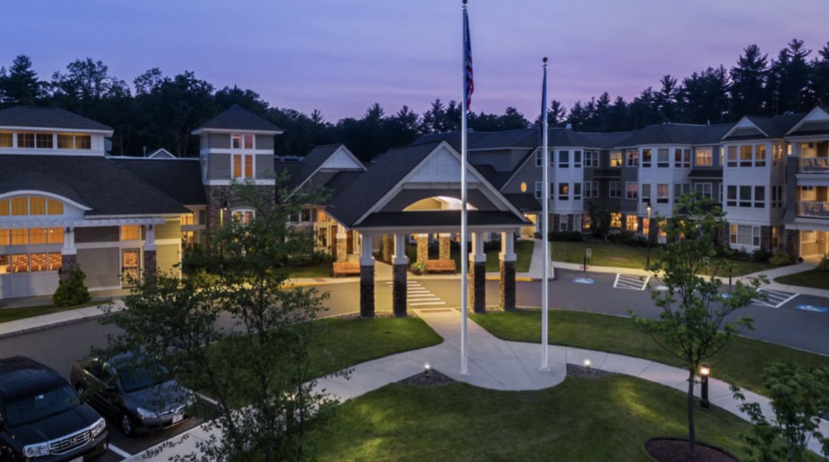 A well-lit building with flags displayed at dusk.