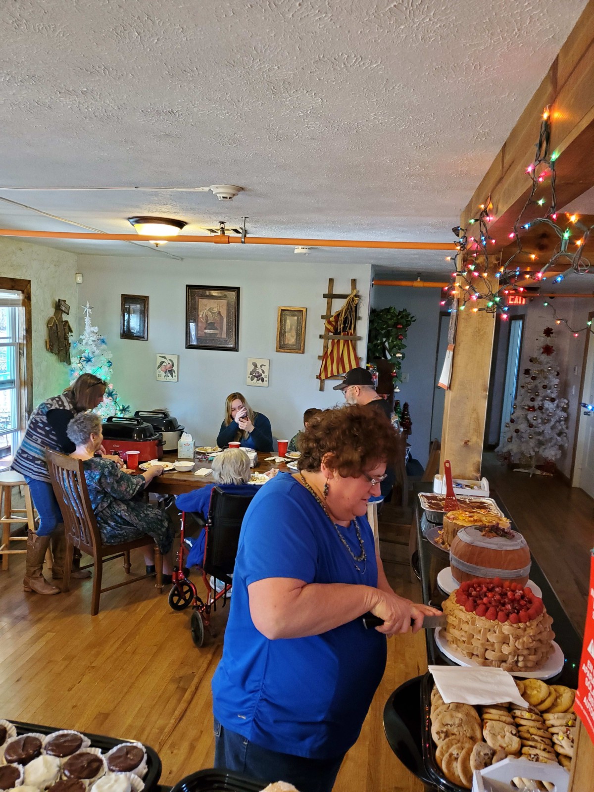 A family gathering with people enjoying food and cake in a decorated dining room.