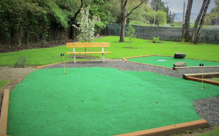 A serene outdoor mini golf course with a bench for relaxation.