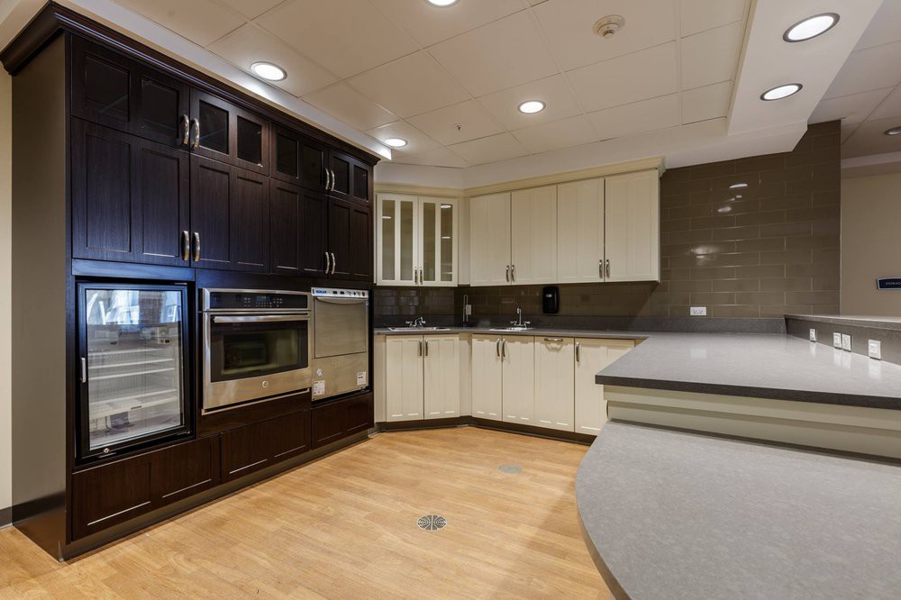 A modern kitchen with dark and light cabinetry, wood flooring, and built-in appliances.