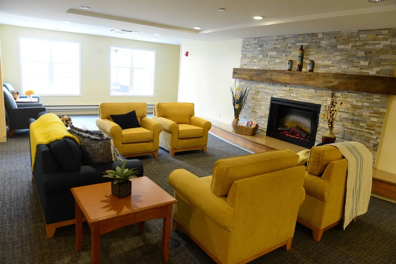 A cozy living room with yellow chairs and a stone fireplace.