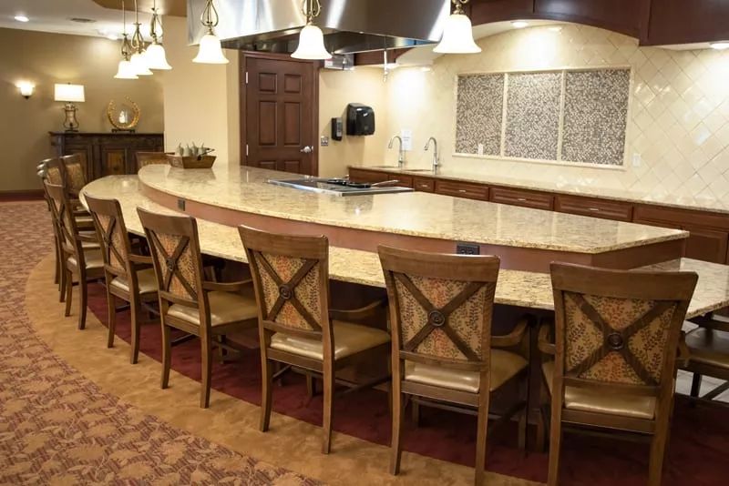 A modern kitchen with a large countertop and wooden bar stools.