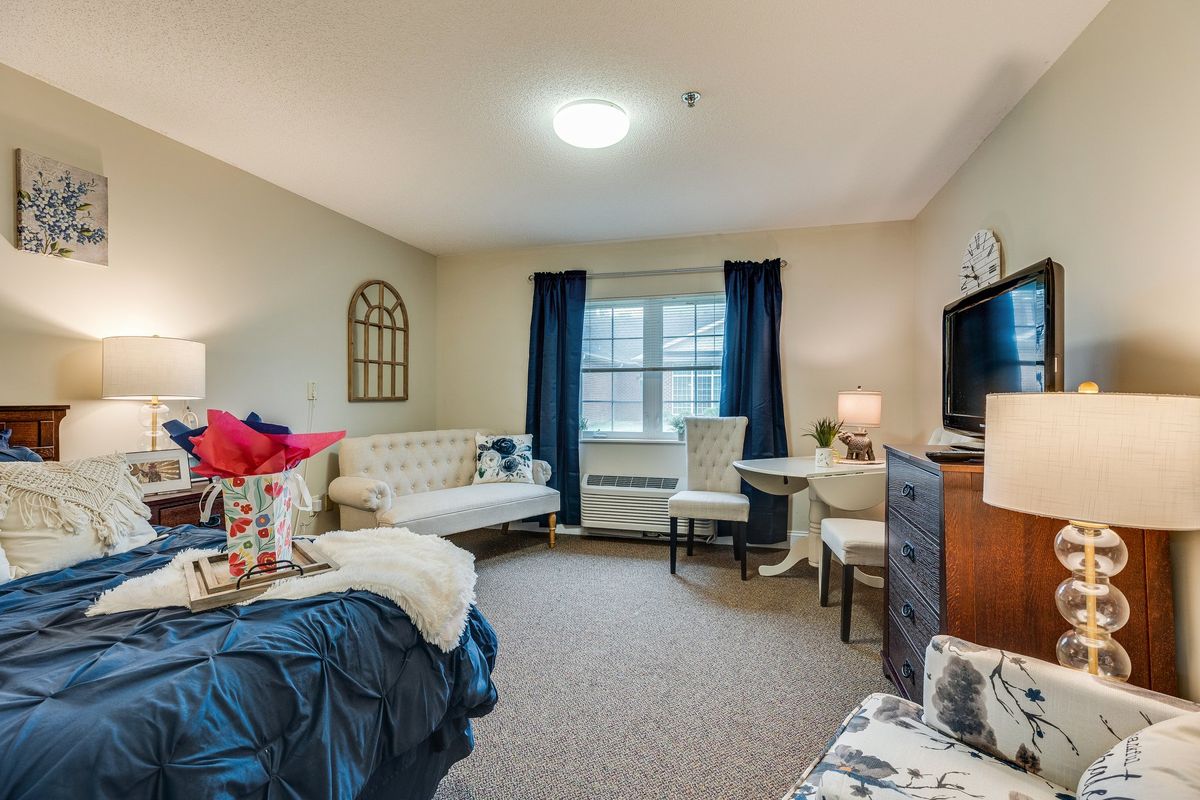 A cozy and well-decorated living space featuring a bed, sofa, table with chairs, and a television.
