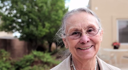 A joyful older woman enjoying the outdoors with a warm smile.