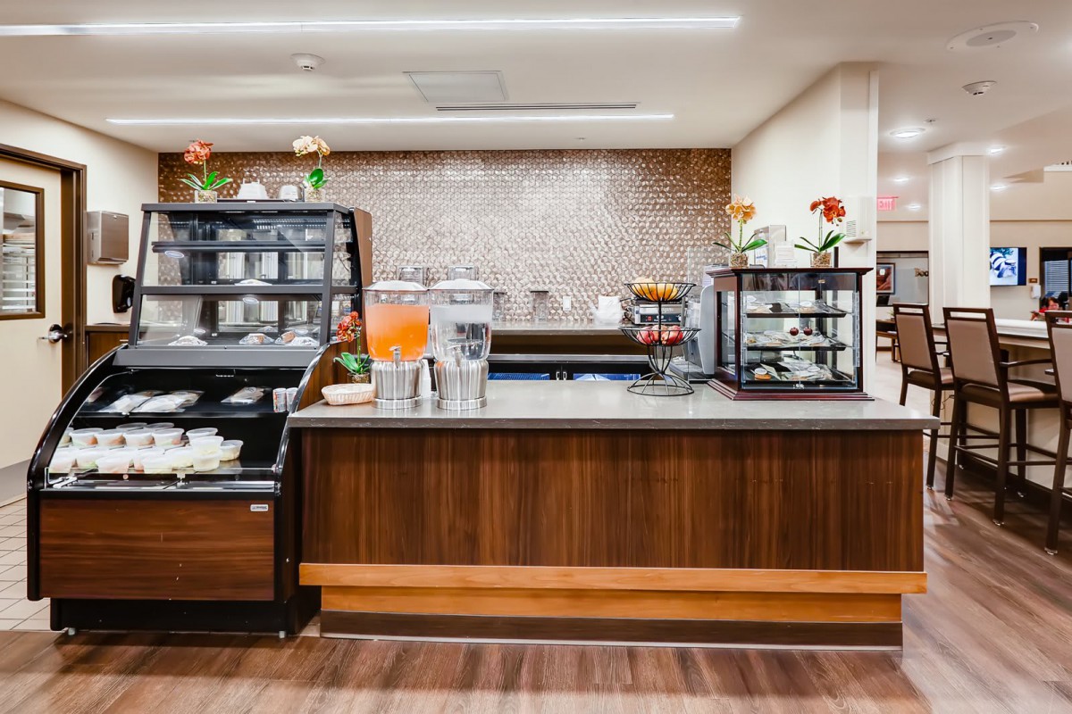 A modern cafe counter with a variety of beverages and food displays.