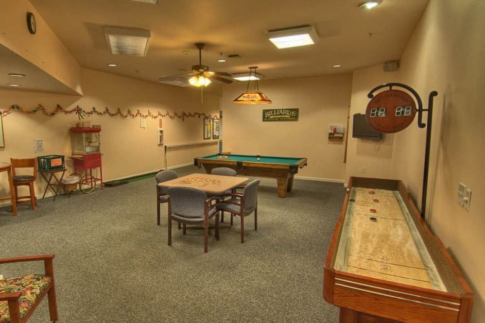 A cozy game room featuring a pool table, shuffleboard, and a table with chairs.