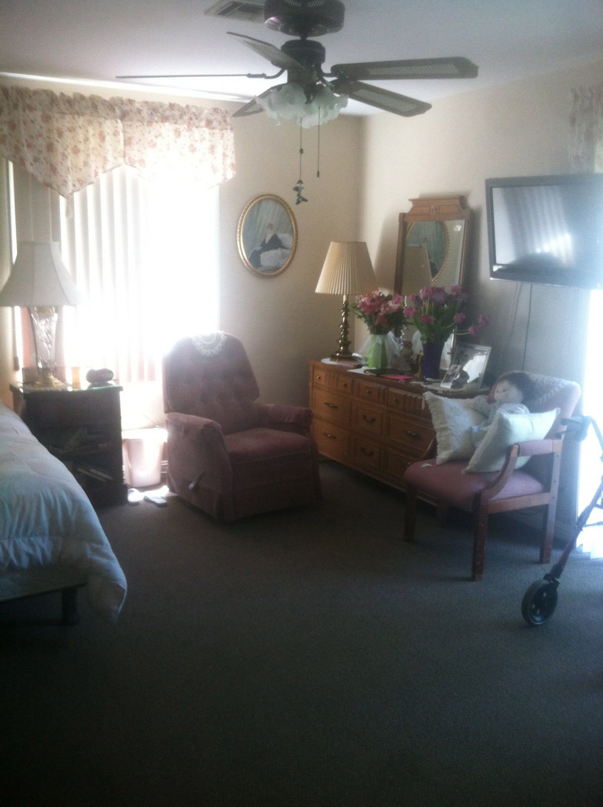 A cozy bedroom interior featuring a bed, chairs, dresser with mirror, and lamps.