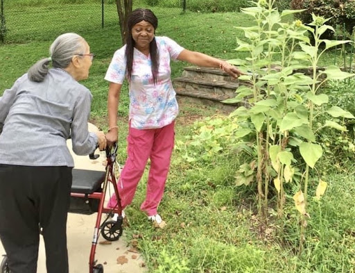 Two individuals engaging in conversation near sunflowers in a garden.