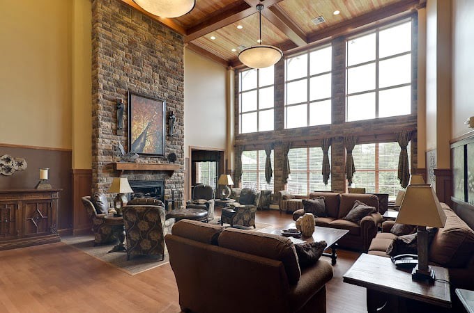 A spacious living room with a stone fireplace, large windows, and comfortable seating.