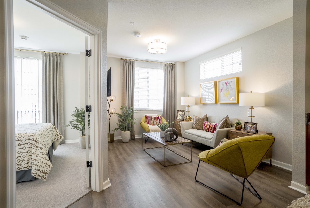 A modern living room with stylish furniture and bright lighting, featuring an open layout and wooden flooring.