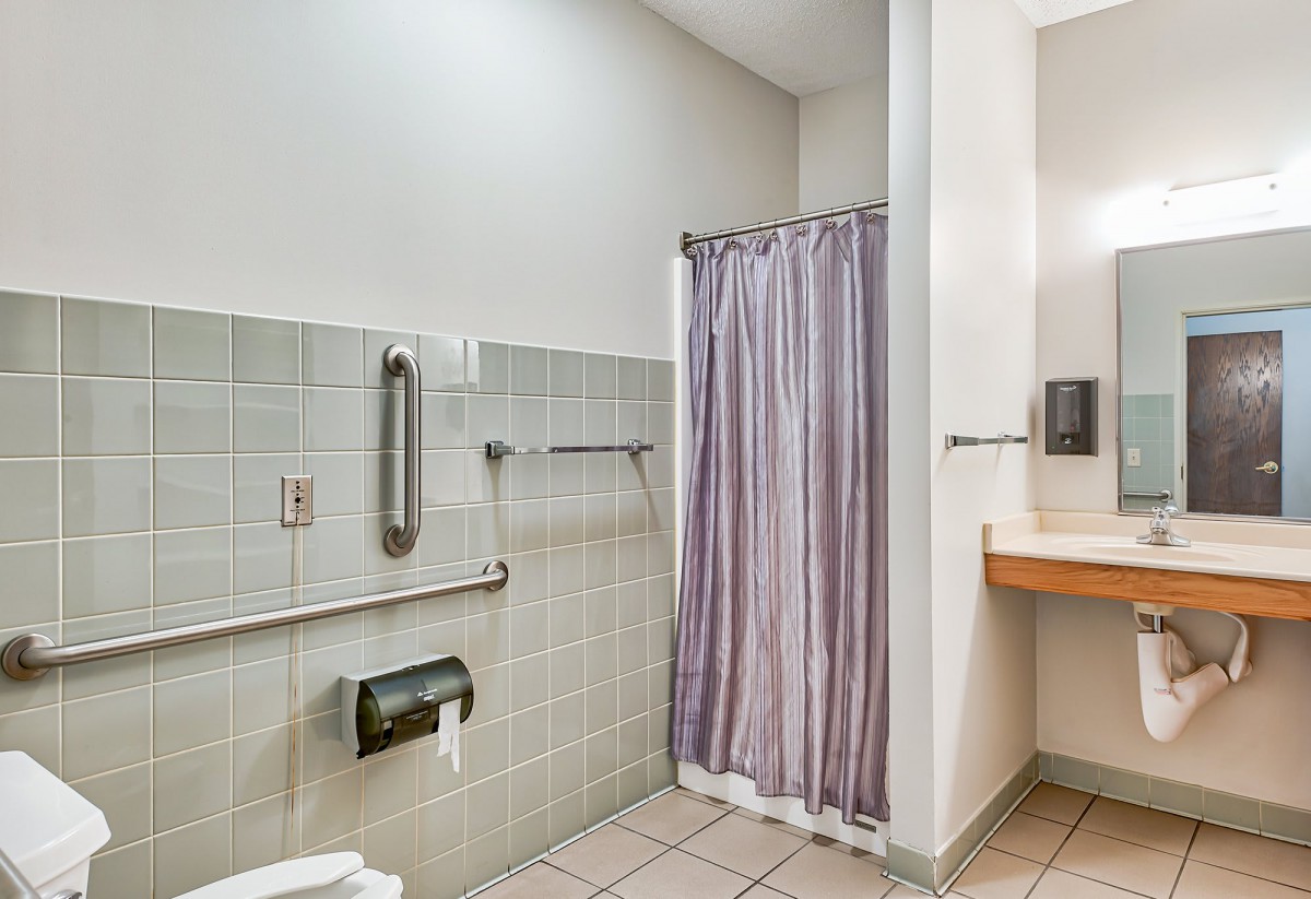 An accessible bathroom with a shower curtain and grab bars.