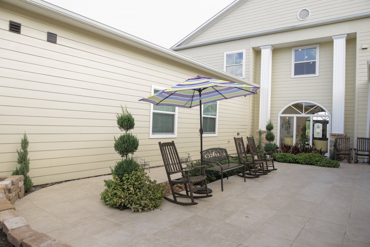 A cozy patio setup with rocking chairs and an umbrella outside a house.