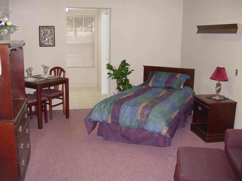 A cozy bedroom with a single bed, table, chairs, and indoor plant.