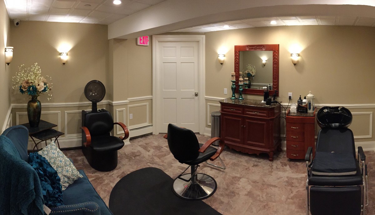 A cozy hair salon with styling chairs and a mirror.