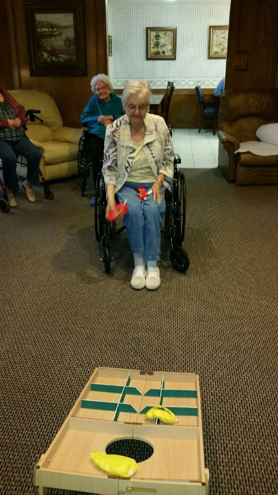 An elderly person in a wheelchair participating in an indoor game.