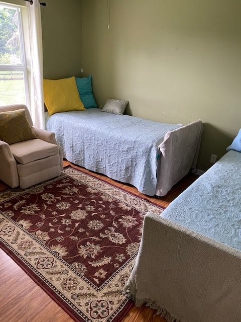 A cozy bedroom with two twin beds, a chair, and a decorative rug.