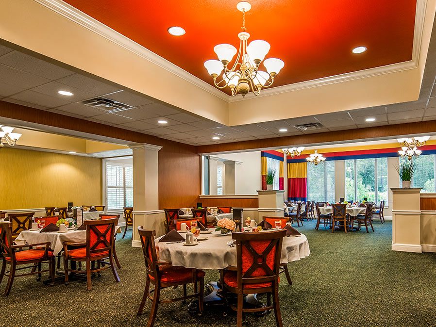 An elegant restaurant dining room with neatly arranged tables and a beautiful chandelier overhead.