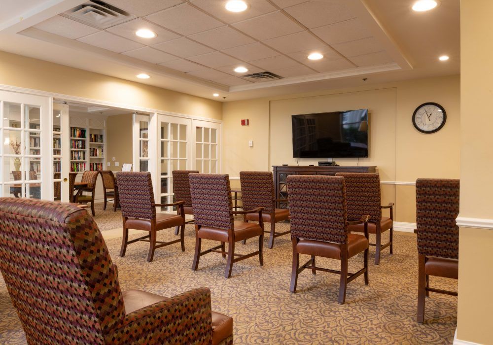 A well-lit conference room with several chairs arranged facing a large television.
