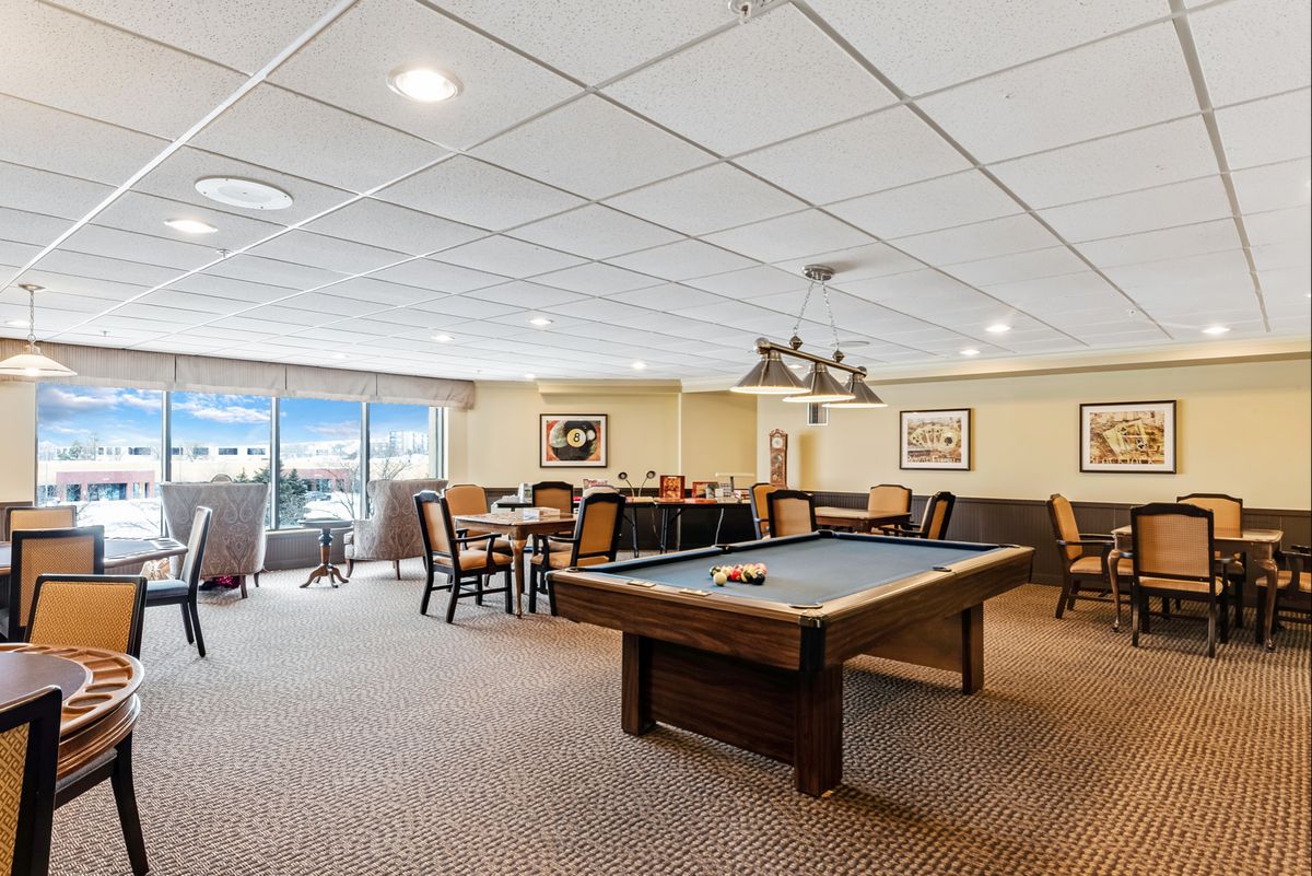 A spacious game room featuring a pool table and seating area.