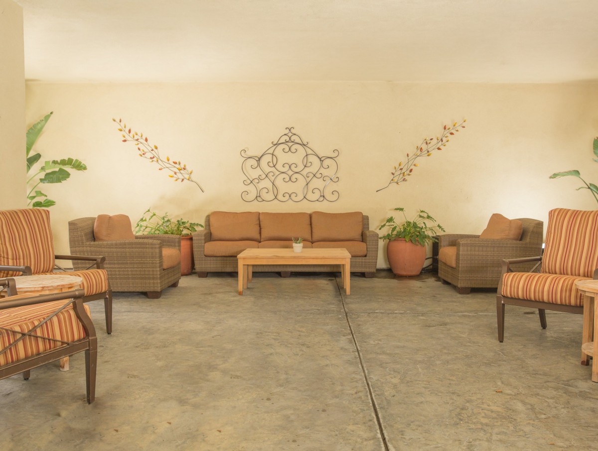 A cozy outdoor seating area with wicker furniture and decorative wall art.