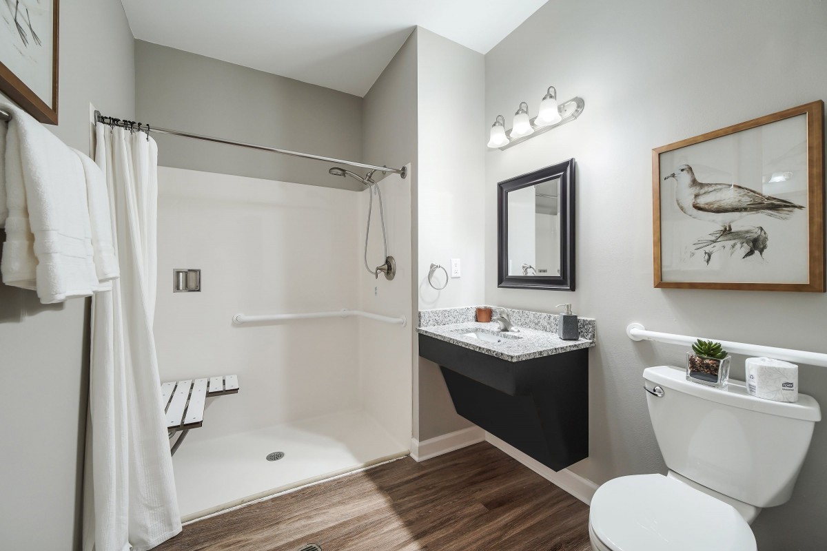 A modern bathroom with a shower, sink, mirror, and toilet.