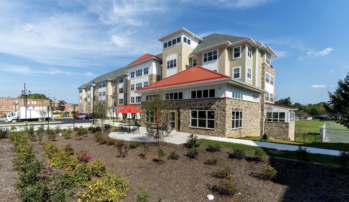 A modern apartment complex with landscaped surroundings under a clear blue sky.