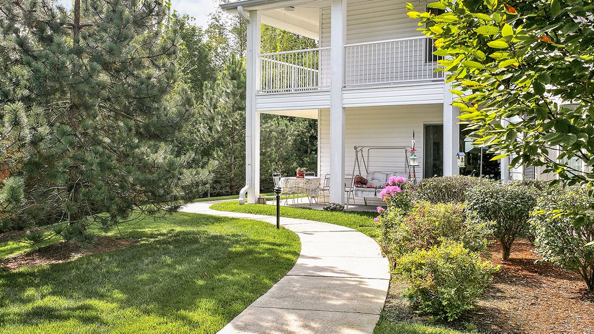 A charming house with a wrap-around porch and landscaped garden path.