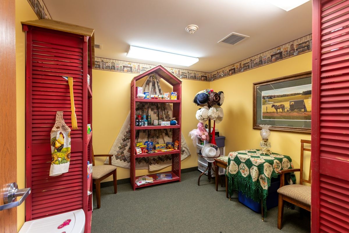 A cozy waiting room designed for children, featuring a bookshelf shaped like a house filled with books and toys, along with comfortable chairs and colorful decorations.