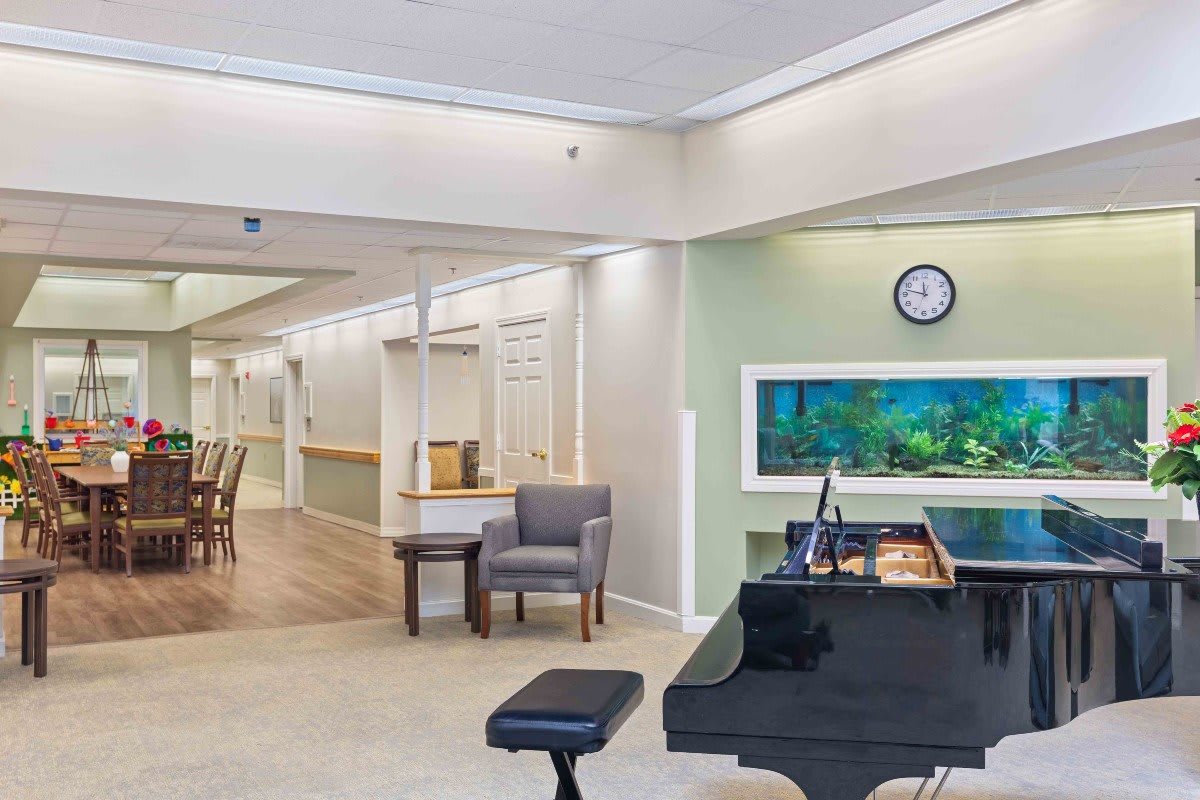 A welcoming lobby area featuring a piano, comfortable seating, and an aquarium along the wall.