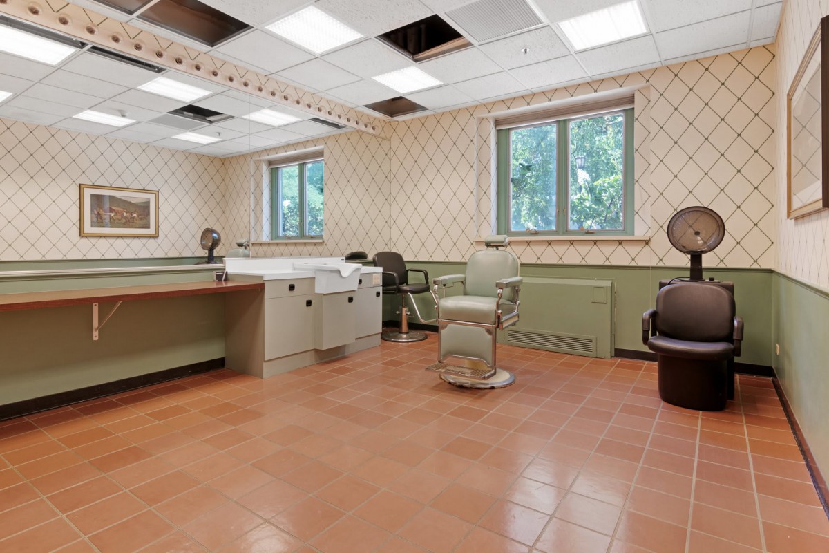 An empty hair salon featuring barber chairs and mirrors, with natural light coming through the windows.