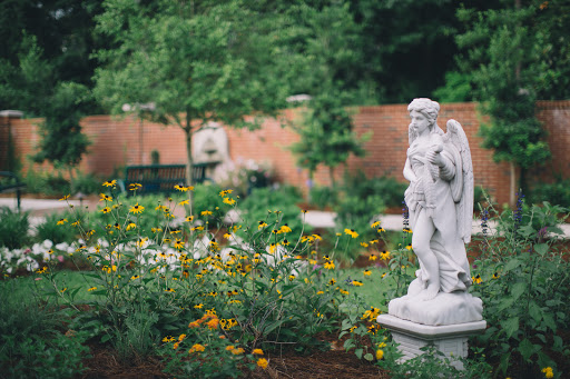 A serene garden adorned with colorful flowers and a majestic angel statue, creating a peaceful atmosphere.
