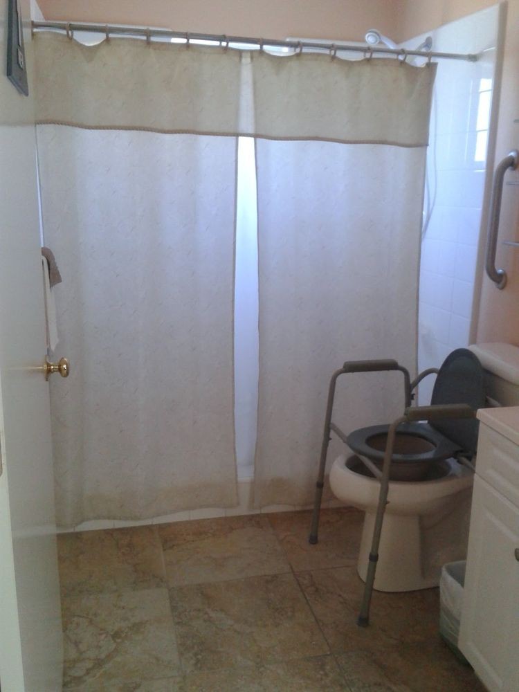 An accessible bathroom with a toilet and grab bar next to a shower area.