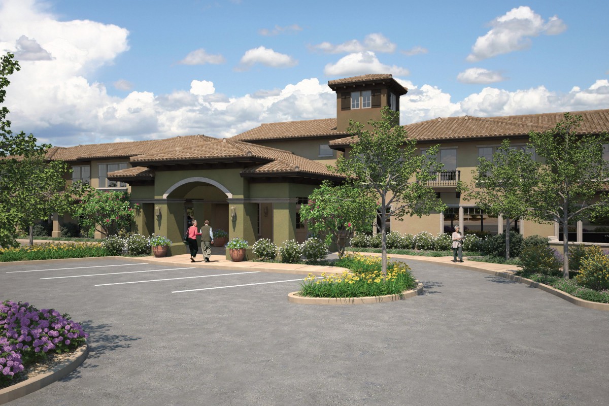 An elegant building with an arched entrance surrounded by landscaped greenery.