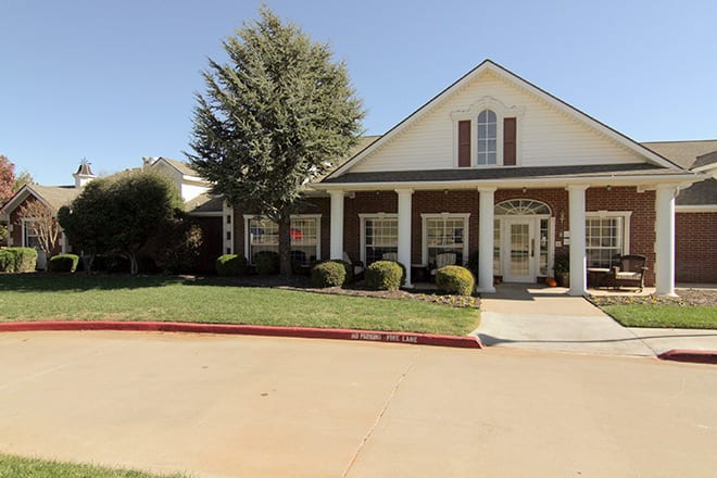 A residential house with a front lawn and driveway on a sunny day.