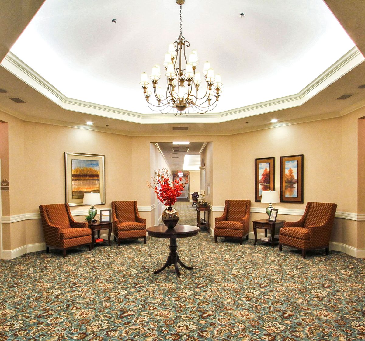 A well-furnished lobby with a chandelier, comfortable seating, and decorative artwork.